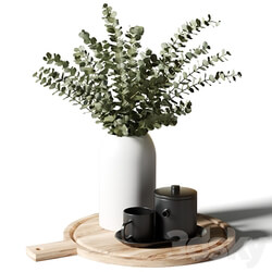 A bouquet of eucalyptus in a white vase and a teapot with a cup on a wooden board 